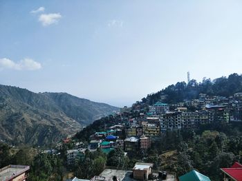 Aerial view of townscape and mountains against sky