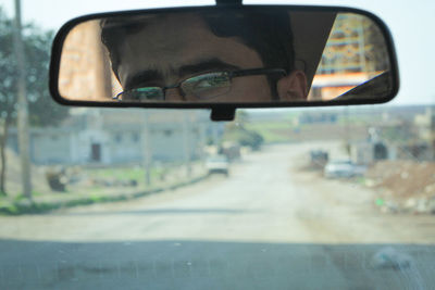 Close-up portrait of reflection of car on side-view mirror