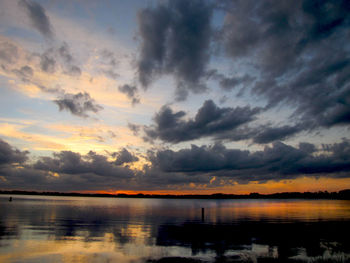 Scenic view of lake against dramatic sky during sunset
