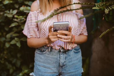 Midsection of woman photographing with mobile phone