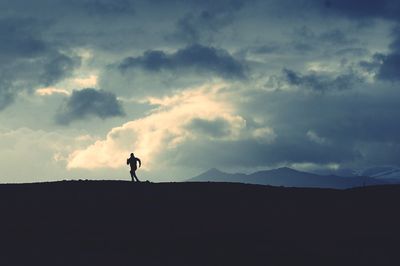 Silhouette man standing on field against sky during sunset