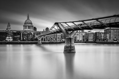 London millennium footbridge over thames river by st paul cathedral against sky
