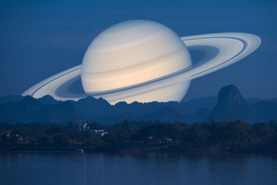 Scenic view of lake by mountains against sky at night