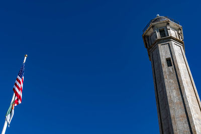 Low angle view of flag on building against clear blue sky