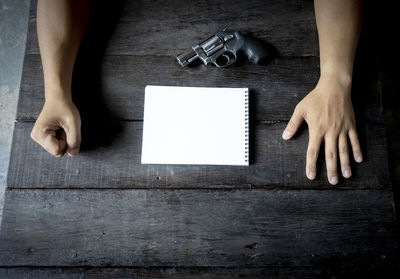 Close-up of businessman with gun and note pad on table 