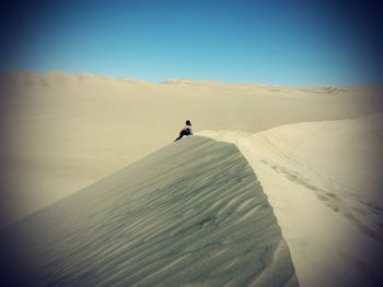 Woman sitting on sand dune at desert