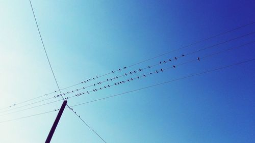 Low angle view of power lines against clear blue sky