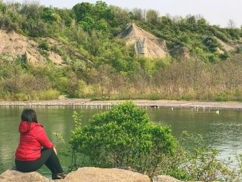 Rear view of woman looking at lake against trees