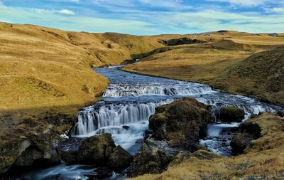 Scenic view of waterfall against sky