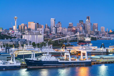 Boats in harbor by buildings against clear sky