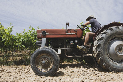 Side view of farmer sitting on tractor at farm during sunny day