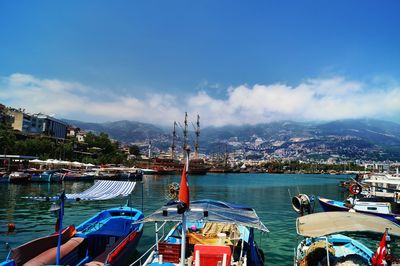 Boats moored at harbor against blue sky