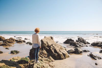 Woman standing on beach against clear sky