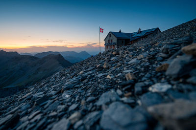 Surface level of land against house and sky during sunset