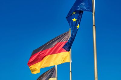 Low angle view of flags against clear blue sky