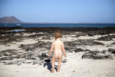 Full length of shirtless boy on beach