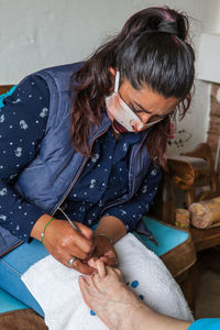 Woman wearing mask doing pedicure to patient