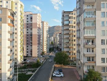 Vehicles on road by buildings in city against sky