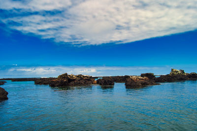 Rock formations in sea against blue sky