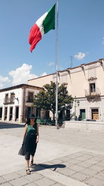 Woman with umbrella flag against buildings in city