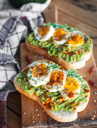 Close-up of avocado and egg toast with herbs and seasonings, on cutting board