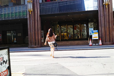 Full length of woman with umbrella on road in city