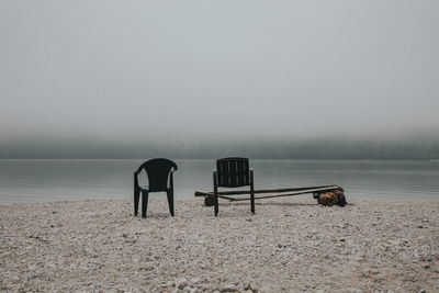 Empty seats in lake against sky