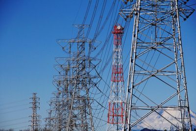 Low angle view of electricity pylon against blue sky