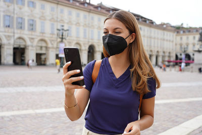 Young woman using mobile phone in city