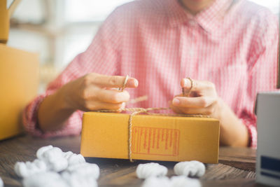 Midsection of woman tying knot of box