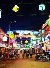 People at illuminated market in city at night