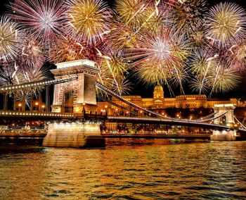 Illuminated bridge over river at night