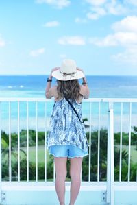 Woman standing by railing against sea