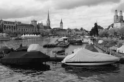 Boats moored on river in city against sky