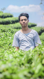 Portrait of young man standing amidst plants