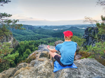Rear view of man standing on rock against sky