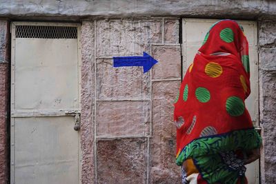 Woman wearing sari walking against arrow sign on wall