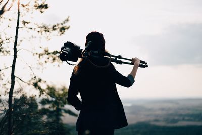 Female photographer holding photographic camera on stand