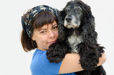 Portrait of woman hugging cocker spaniel against white background