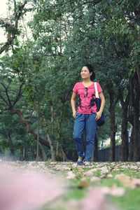 Full length of young woman standing against trees