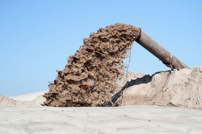 Low angle view of rock against clear blue sky