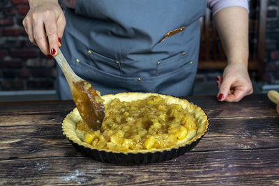 Women preparing  apple tart or pie .spreading the cooked candied apple over the dough