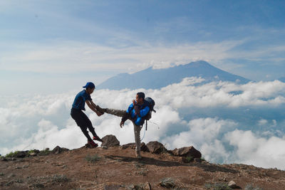 Men on rock against sky