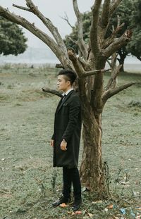 Side view of man standing on by tree field