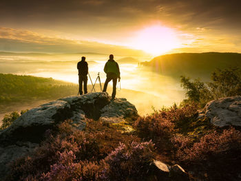 Two landscape photographers taking photos of mountain rang. heavy mist in beautiful nature view