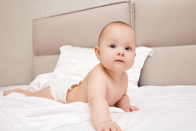 Cute baby boy lying on bed at home