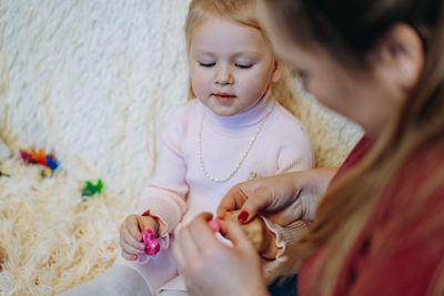 Mother applying nail polish on daughters nail
