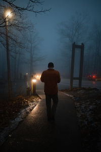 Rear view of man standing on street at night