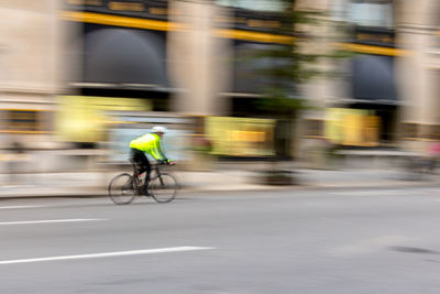 Man cycling on street against building in city