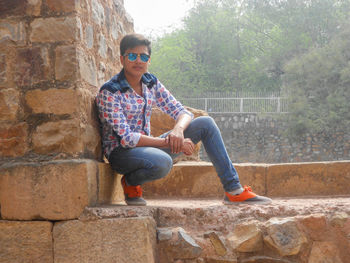 Full length of boy sitting on wall